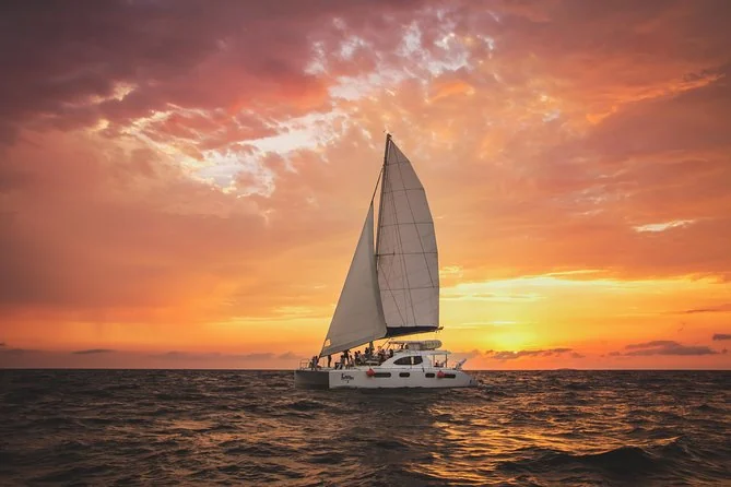 Un velero a vela desplegada al atardecer en la bahía de Banderas
